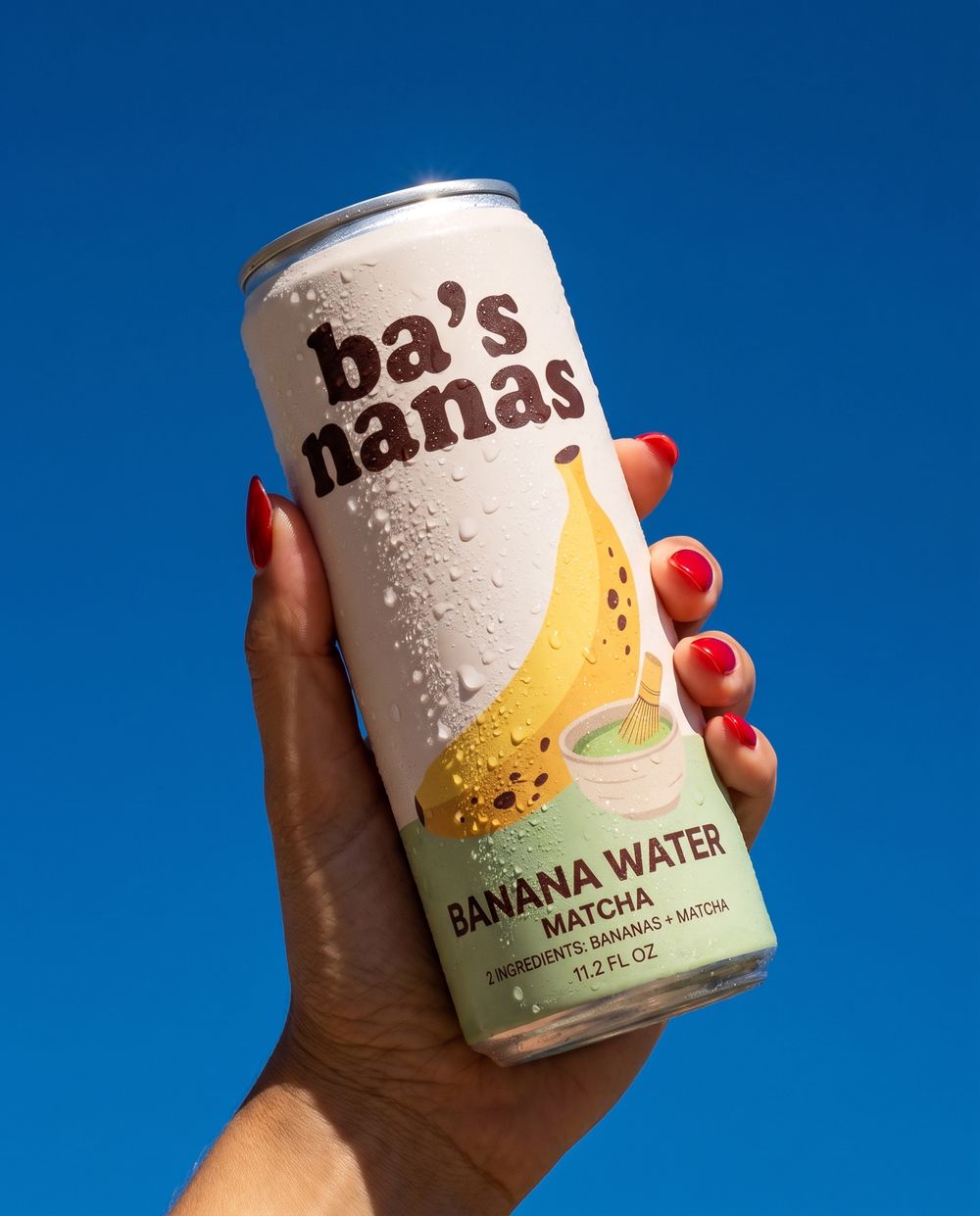A hand holding an Original can against a blue sky