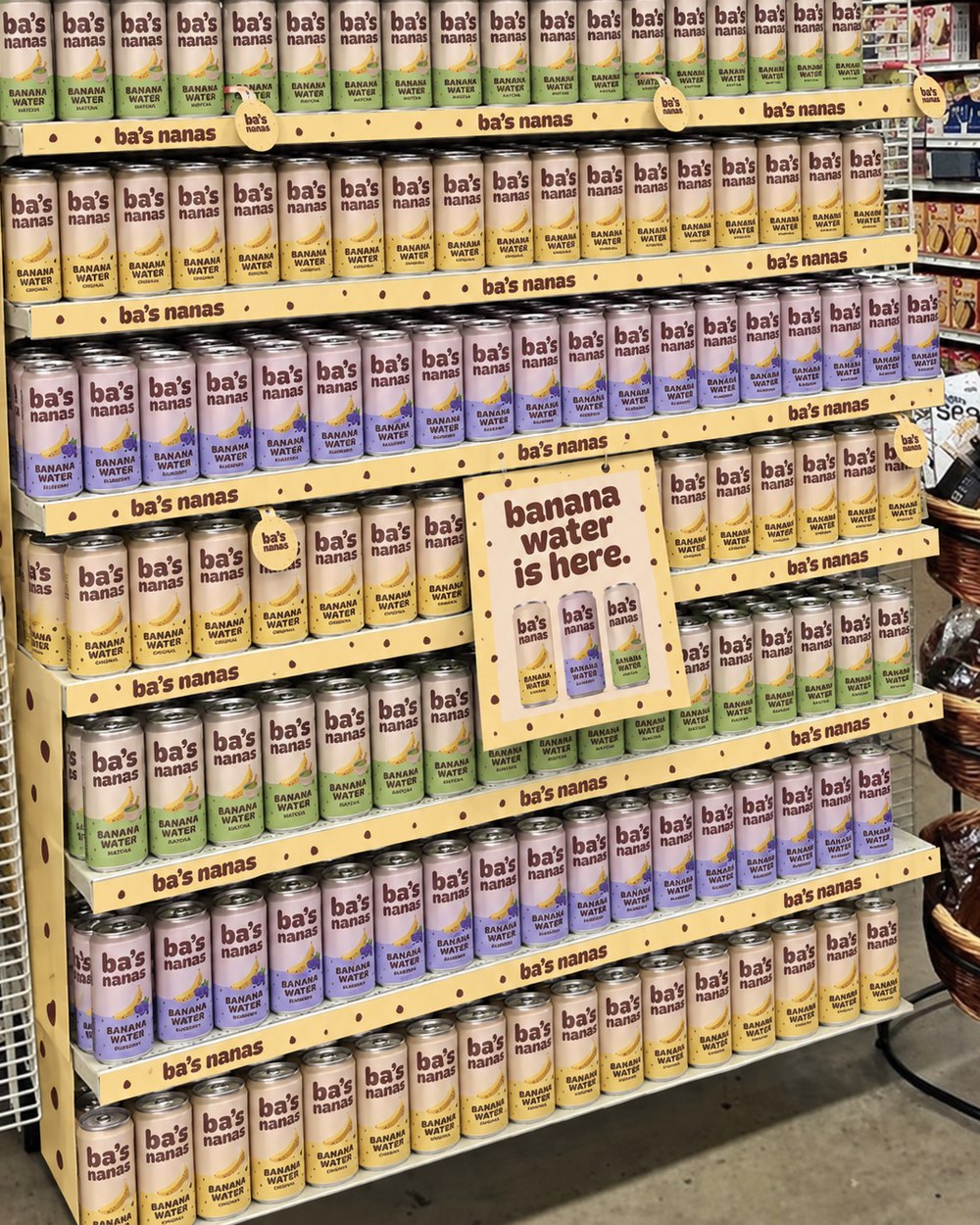 A Ba's Nanas endcap with four shelves of cans and branded cases in a grocery store