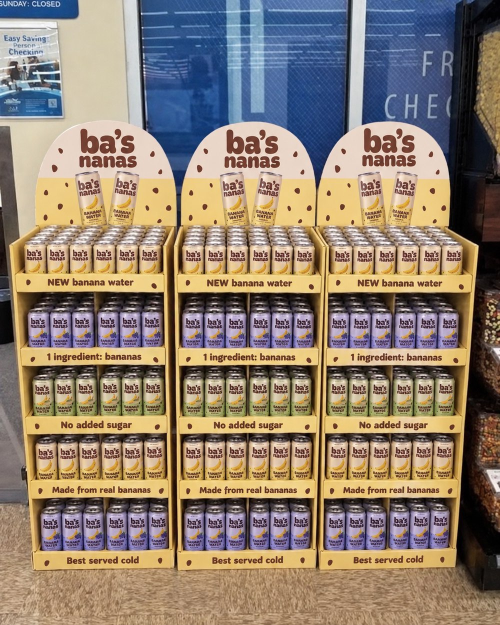 A Ba's Nanas floor shipper in can colours, full of cans, in a grocery produce section